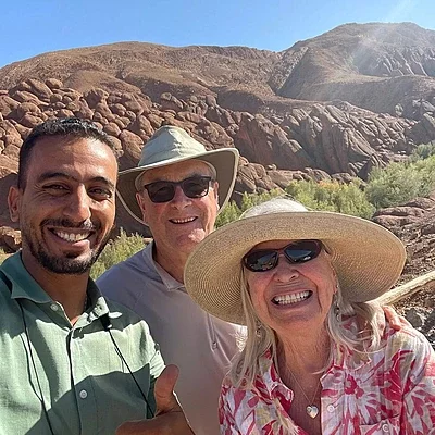 our driver hassa with happy clienst from the united states smiling close to a camel in merzouga